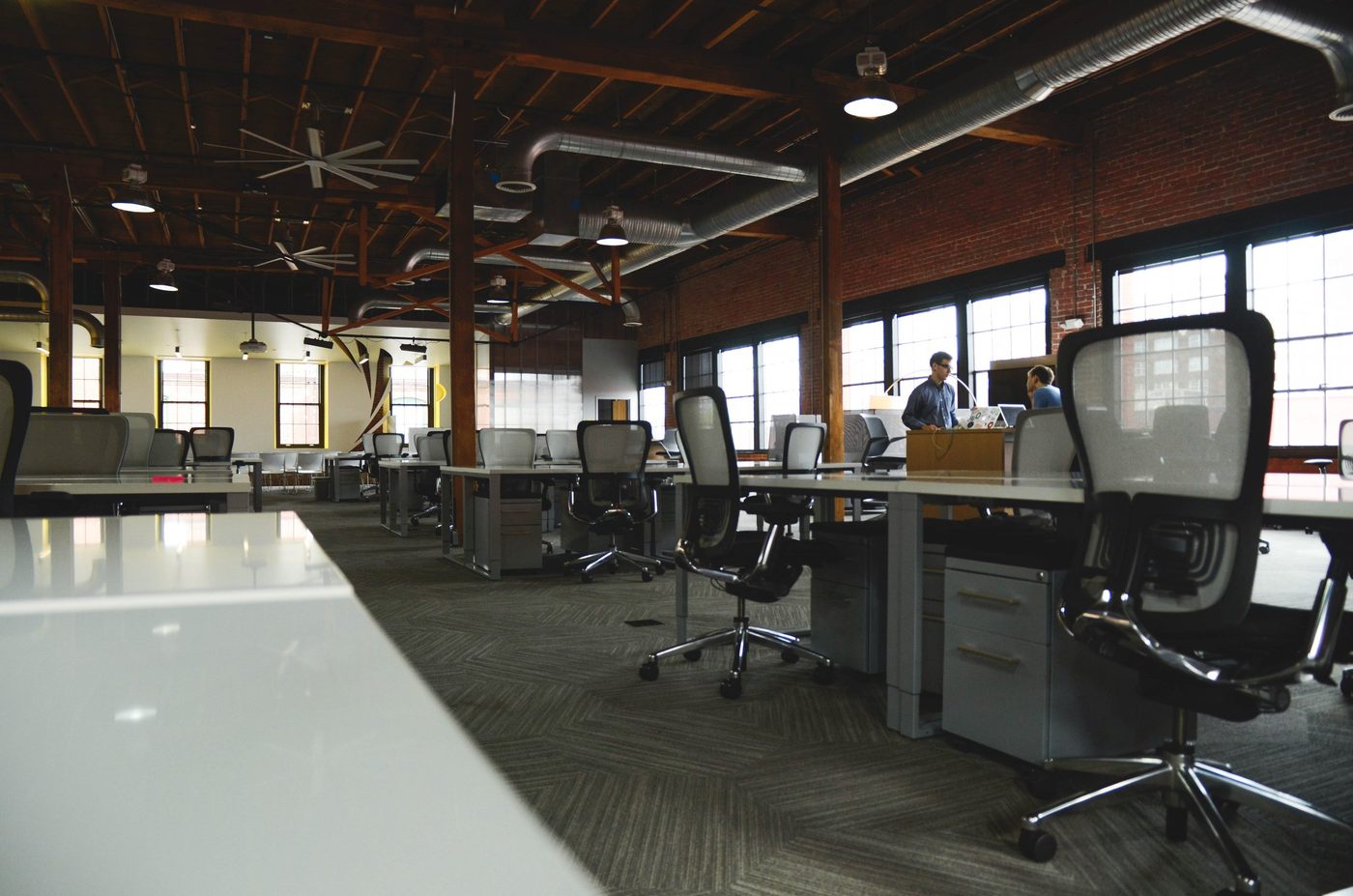 Interior of an open office floor plan with desks, chairs, and exposed ceilings.